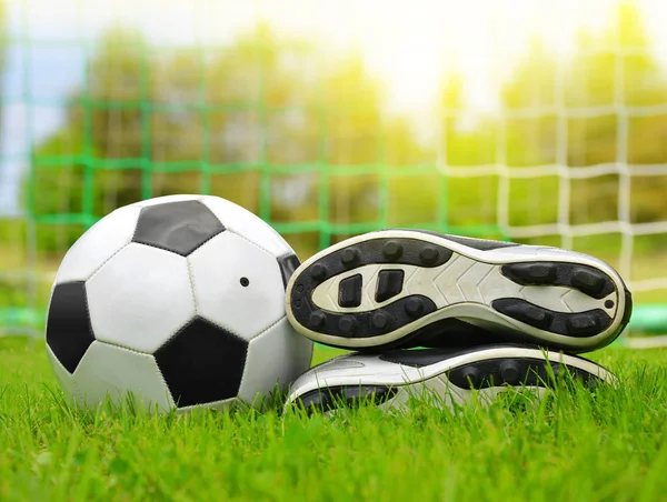 Soccer ball and shoes in grass. — Stock Photo, Image