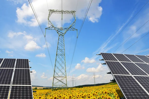 Solar panels with electricity pylons in sunflower field. — Stock Photo, Image