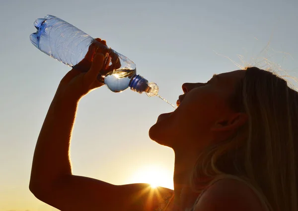 Silhouette of a woman drinking water from bottle. — Stock Photo, Image