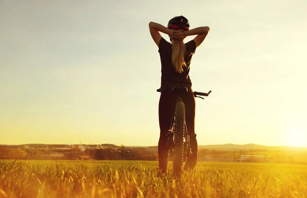 Chica en una bicicleta en la puesta del sol . —  Fotos de Stock