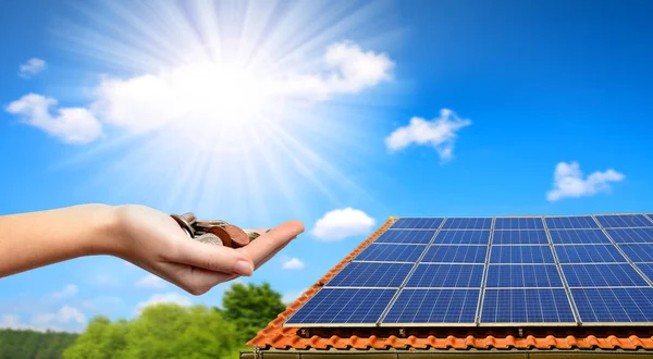 Solaranlage auf dem Dach des Hauses und Münzen in der Hand. — Stockfoto