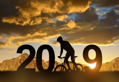 Bir bisikletçi bisiklet günbatımında silüeti. Yeni yıl 2019 kavramı.