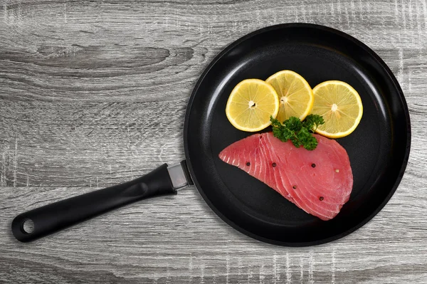 木製の背景にフライパンにレモンのスライスと新鮮なマグロ ステーキ — ストック写真