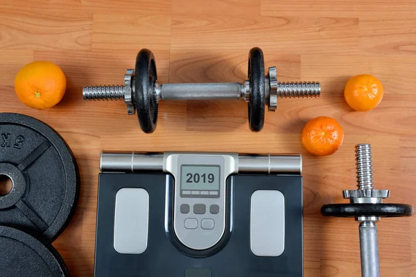 黑色哑铃与金属圆盘和体重秤在健身房 2019新年健康解决方案 — 图库照片