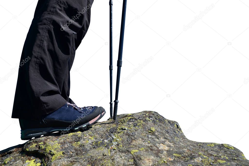 Nordic walking sticks and legs of a mountain hiker with hiking boots on a rock.
