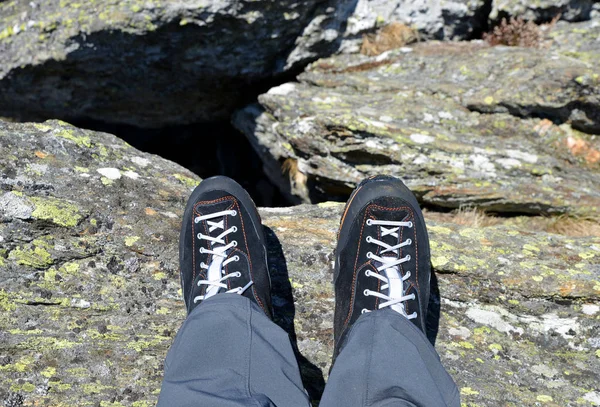 Legs of a mountain hiker with hiking boots on a rock.