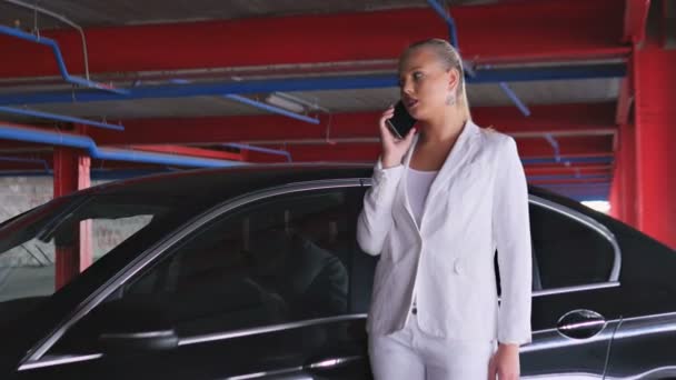 Дівчина розмовляє по телефону біля автомобіля — стокове відео