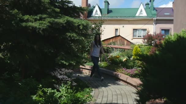 Ung vacker flicka gå längs en väg i trädgården — Stockvideo