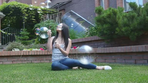 Девушка надувает мыльные пузыри в саду — стоковое видео