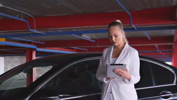 Mädchen mit Tablet auf dem Parkplatz neben dem Auto — Stockvideo