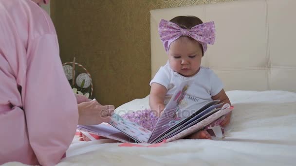 Маленькая девочка учится читать с мамой — стоковое видео