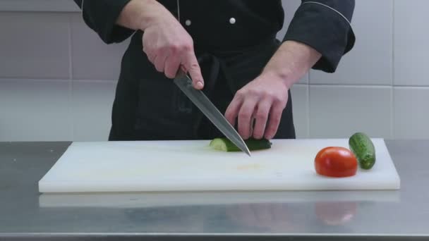 Man snijdt een komkommer in de keuken — Stockvideo