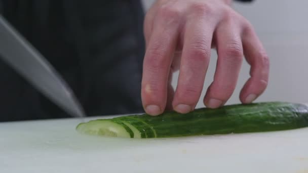 Homem está cortando um pepino na cozinha — Vídeo de Stock