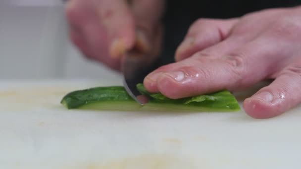 Cozinheiro profissional na cozinha corta um pepino — Vídeo de Stock