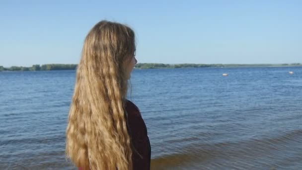 Ung flicka promenader längs stranden av floden kusten — Stockvideo