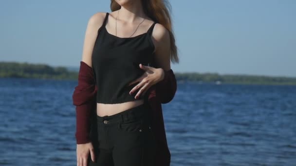 Flicka vidrör sin kropp, stående på stranden av floden — Stockvideo