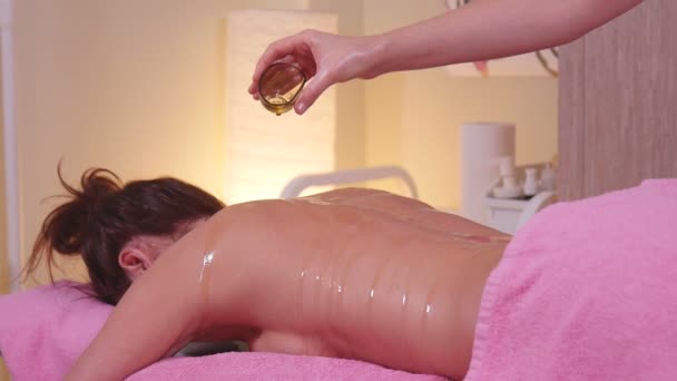 Masseuse pouring oil female back. — Stock Video