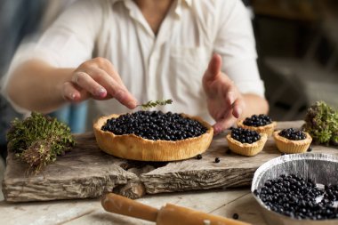 bir adam bir pasta ile ahşap bir masa üzerinde bir whortleberry hazırlar