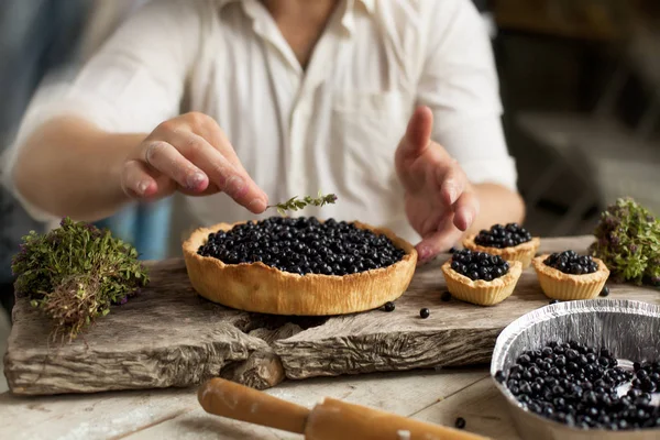 bir adam bir pasta ile ahşap bir masa üzerinde bir whortleberry hazırlar