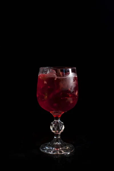 Un bicchiere con una bevanda rossa con ghiaccio su sfondo nero — Foto Stock