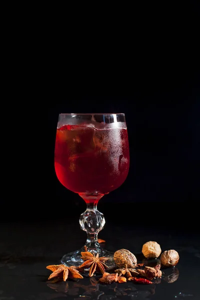 Een glas met een rode drankje met ijs op een zwarte achtergrond — Stockfoto