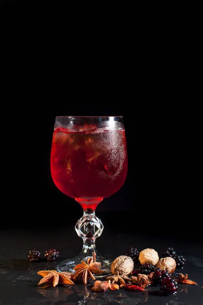 Un verre avec une boisson rouge avec de la glace sur fond noir — Photo