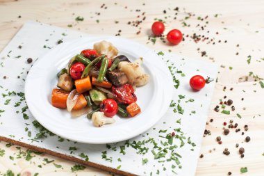 kiraz domates ve yeşillik ile ahşap bir masa üzerinde bir kesme tahtası üzerinde beyaz bir plaka üzerinde ızgara sebze