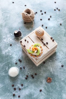 kek kahve çekirdekleri ve mavi bir arka plan iş parçacığı bir arapsaçı ile ışık ahşap kutu üzerine ile pudra şekeri serpilir