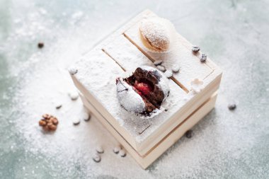 mavi bir arka plan üzerinde kahve çekirdekleri ile ışık ahşap kutusunda kek ile pudra şekeri serpilir