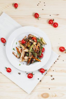 kiraz domates ve yeşillik ile ahşap bir masa üzerinde bir kesme tahtası üzerinde beyaz bir plaka üzerinde ızgara sebze