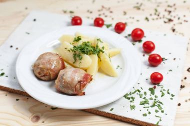 yeşillikleri ile beyaz tabakta et ve beyaz kesme tahtası ahşap bir masa üzerinde kiraz domates ile patates