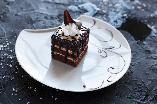 Çikolatalı Pasta krema ve çikolata çilek siyah bir zemin üzerine beyaz bir tabakta ile süslenmiş