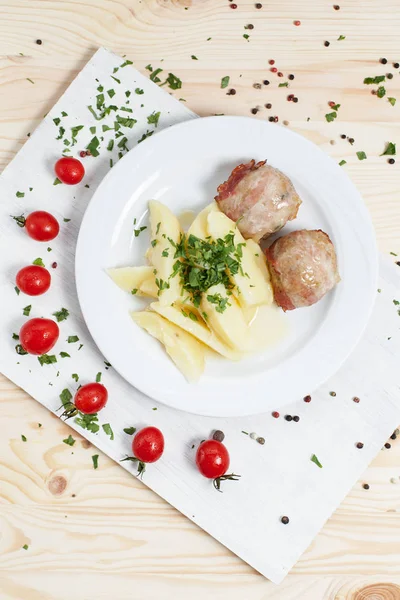 야채와 함께 흰색 접시에 고기와 나무 테이블에 화이트 커팅 보드에 체리 토마토와 감자 — 스톡 사진
