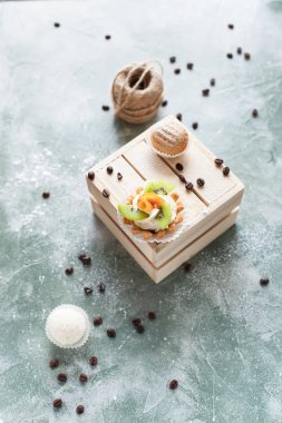 kek kahve çekirdekleri ve mavi bir arka plan iş parçacığı bir arapsaçı ile ışık ahşap kutu üzerine ile pudra şekeri serpilir