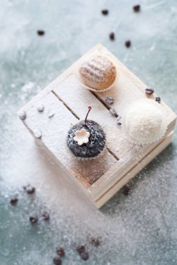 mavi bir arka plan üzerinde kahve çekirdekleri ile ışık ahşap kutusunda kek ile pudra şekeri serpilir