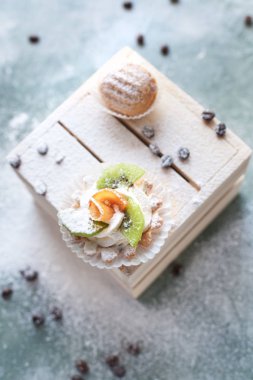 mavi bir arka plan üzerinde kahve çekirdekleri ile ışık ahşap kutusunda kek ile pudra şekeri serpilir