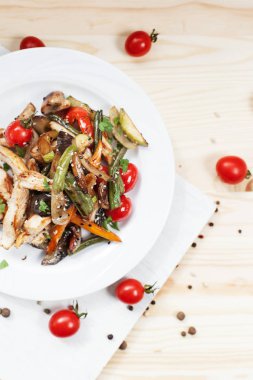 kiraz domates ve yeşillik ile ahşap bir masa üzerinde bir kesme tahtası üzerinde beyaz bir plaka üzerinde ızgara sebze