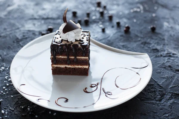 Çikolatalı Pasta krema ve çikolata çilek siyah bir zemin üzerine beyaz bir tabakta ile süslenmiş