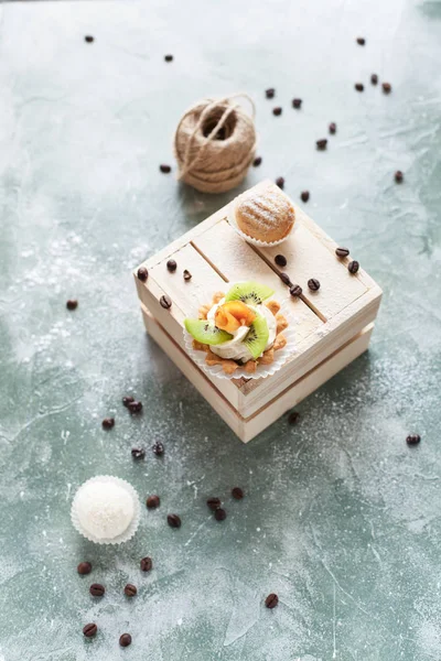 kek kahve çekirdekleri ve mavi bir arka plan iş parçacığı bir arapsaçı ile ışık ahşap kutu üzerine ile pudra şekeri serpilir