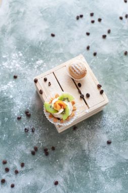 mavi bir arka plan üzerinde kahve çekirdekleri ile ışık ahşap kutusunda kek ile pudra şekeri serpilir