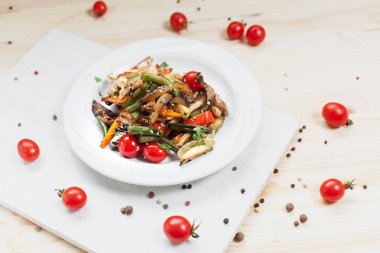 kiraz domates ve yeşillik ile ahşap bir masa üzerinde bir kesme tahtası üzerinde beyaz bir plaka üzerinde ızgara sebze