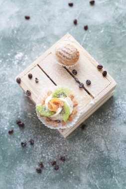 mavi bir arka plan üzerinde kahve çekirdekleri ile ışık ahşap kutusunda kek ile pudra şekeri serpilir