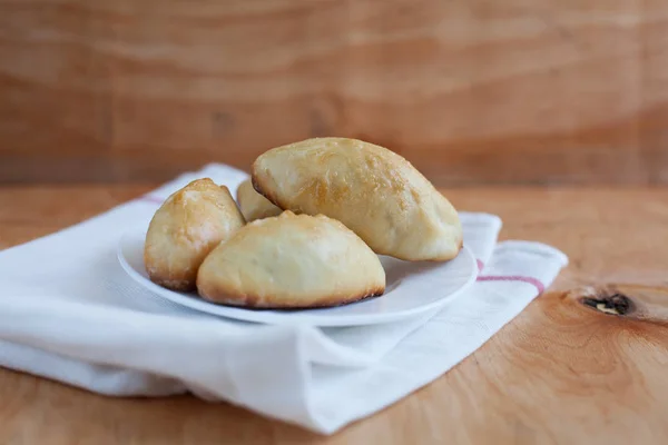 Bir havlu üzerinde ahşap arka plan üzerinde beyaz bir plaka üzerinde ev yapımı börek — Stok fotoğraf