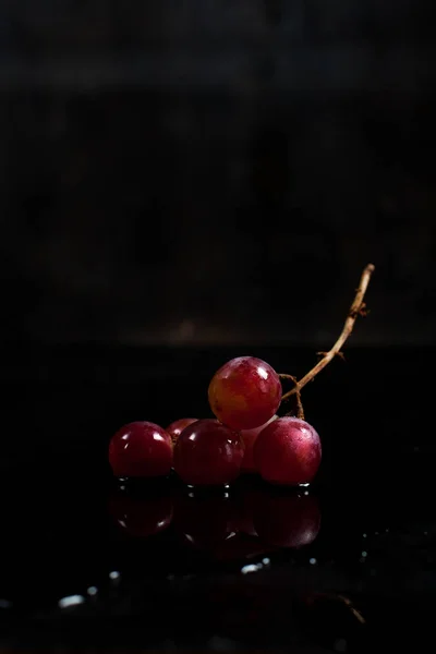Гроздь красного винограда на чёрном фоне с каплями росы — стоковое фото