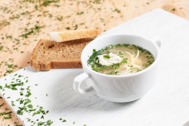 yumurta ve makarna ile Yeşiller ahşap arka plan üzerinde beyaz kesme tahtası üzerinde beyaz bir tabakta et suyu çorbası