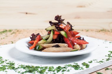 ahşap arka plan üzerinde beyaz bir tahta üzerinde beyaz bir tabakta yeşillikleri ile salatalık, biber, domates, lahana ve tavuk fileto ile sonbahar sebze salatası