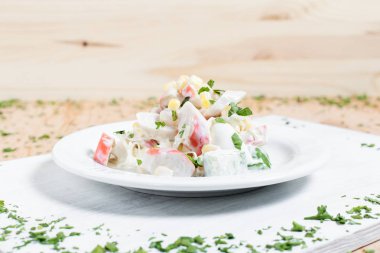 Yengeç sopa, Mısır ve ahşap arka plan üzerinde yeşillikleri ile beyaz kesme tahtası üzerinde beyaz bir tabakta sonbahar sebze salatası