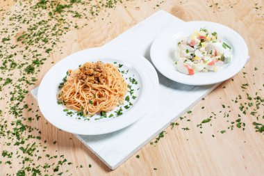 etli makarna ve salata sebze ve yengeç yeşilliklerle çevrili bir ahşap zemin üzerine beyaz kesme tahtası üzerinde beyaz plakalar üzerinde sopa