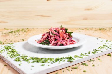 salata sonbahar sebze, lahana, havuç, beyaz kesme tahtası ahşap arka plan üzerinde beyaz bir tabakta yeşillikleri ile