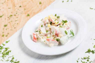 Yengeç sopa, Mısır ve ahşap arka plan üzerinde yeşillikleri ile beyaz kesme tahtası üzerinde beyaz bir tabakta sonbahar sebze salatası